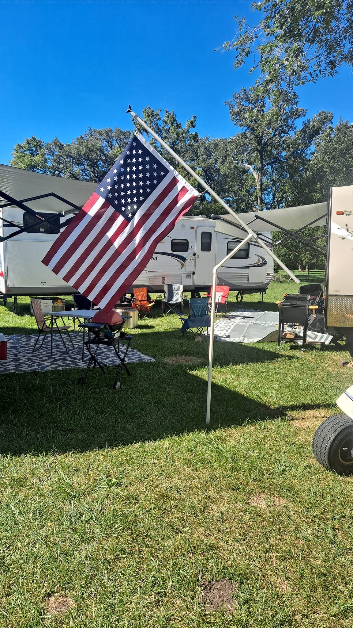 RV campsite at Camp Ziegenhorn with American flag flying over shaded grounds