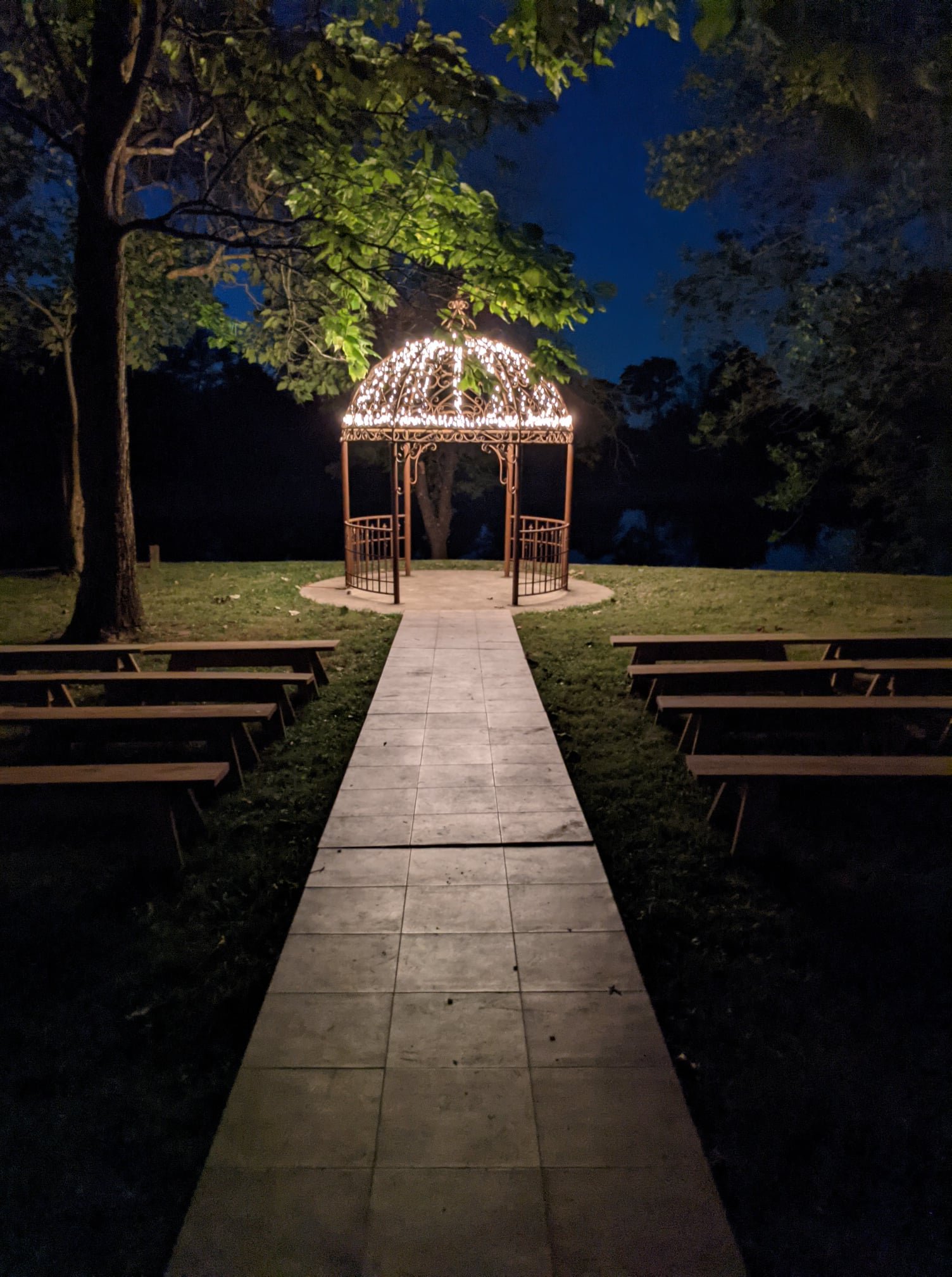 Illuminated wedding gazebo at Camp Ziegenhorn at night with tiled aisle and ceremony benches